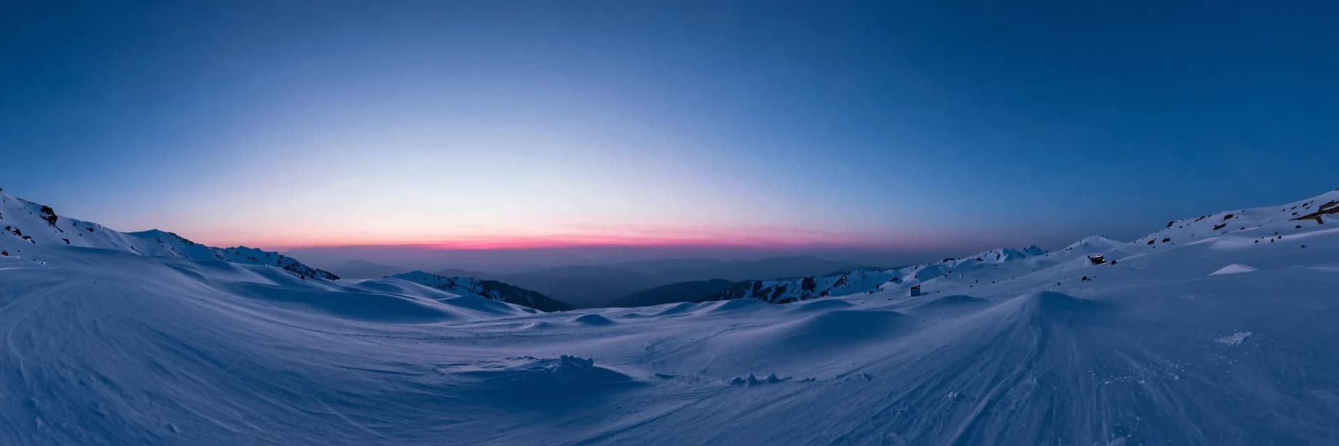 Wide atmospheric interior of an icy cave at dusk, soft pink and blue ambient light through diffuse haze.