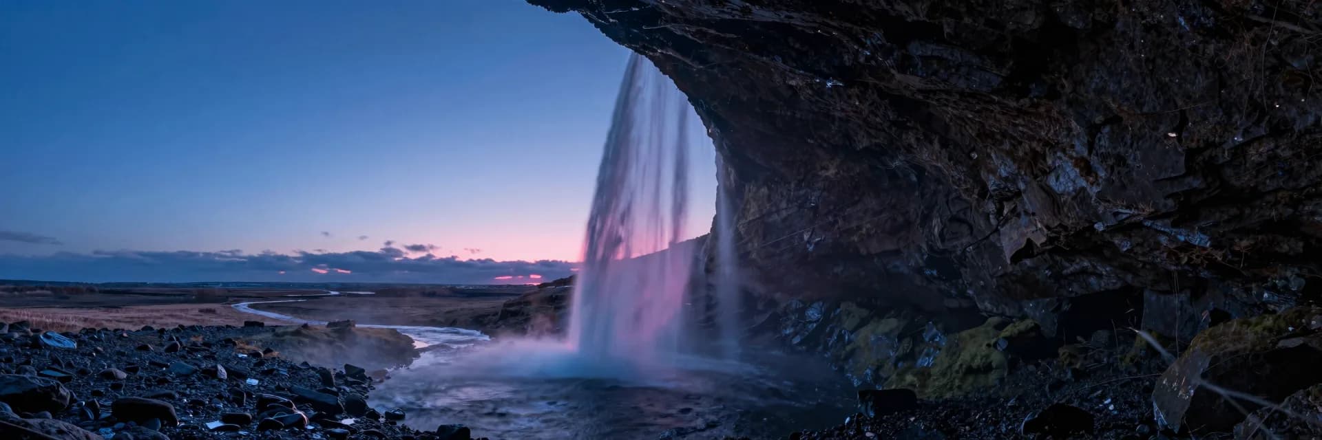 Ultra-wide cave opening framing a frozen waterfall with dramatic horizontal scale.