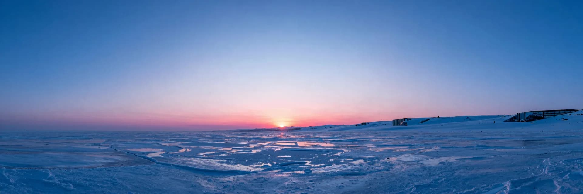 Wide atmospheric interior of an icy cave at dusk, diffuse pink ambient haze filling the negative space.
