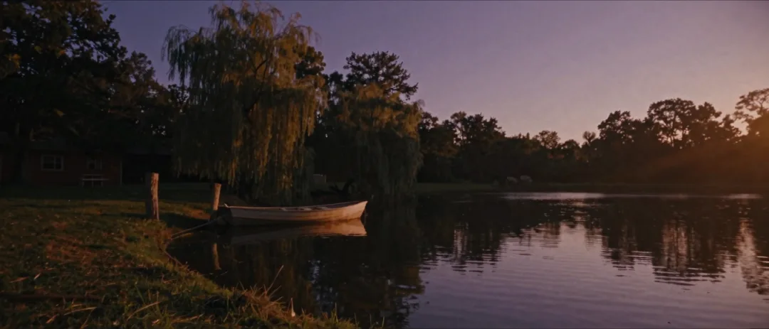 A rowboat resting on a still rural pond at dusk.